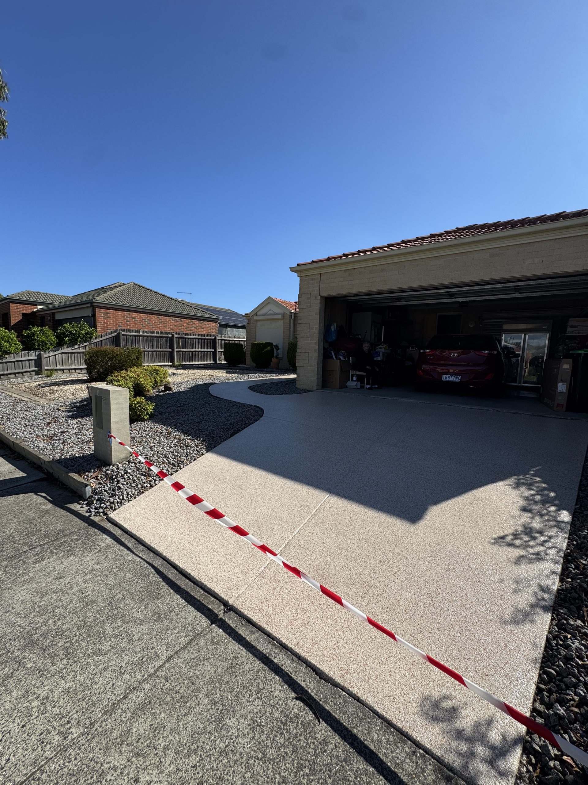 Freshly coated exposed aggregate concrete driveway leading to double garage on residential home