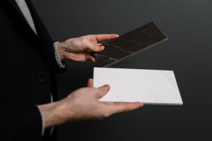 Person comparing black and white marble tile samples for home renovation or interior design